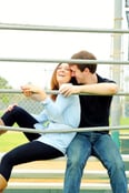 two people happily snuggling on bleachers