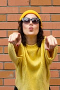 woman in yellow clothes pointing 2 fingers towards you